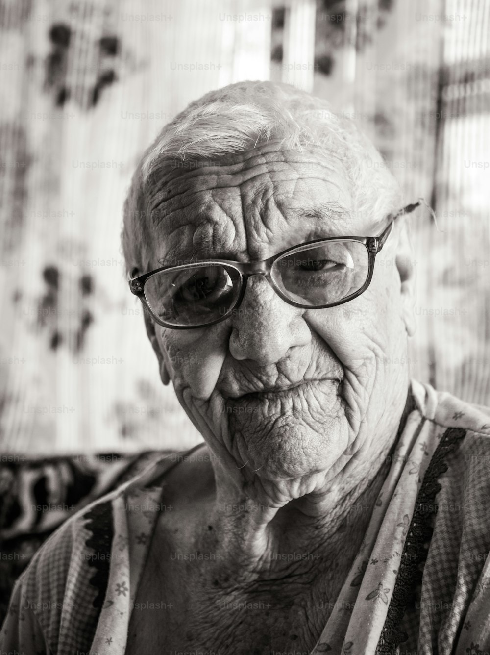 Retrato en blanco y negro de una anciana arrugada de cien años. Una abuela sonriente con grandes gafas. Edad, bondad y sabiduría