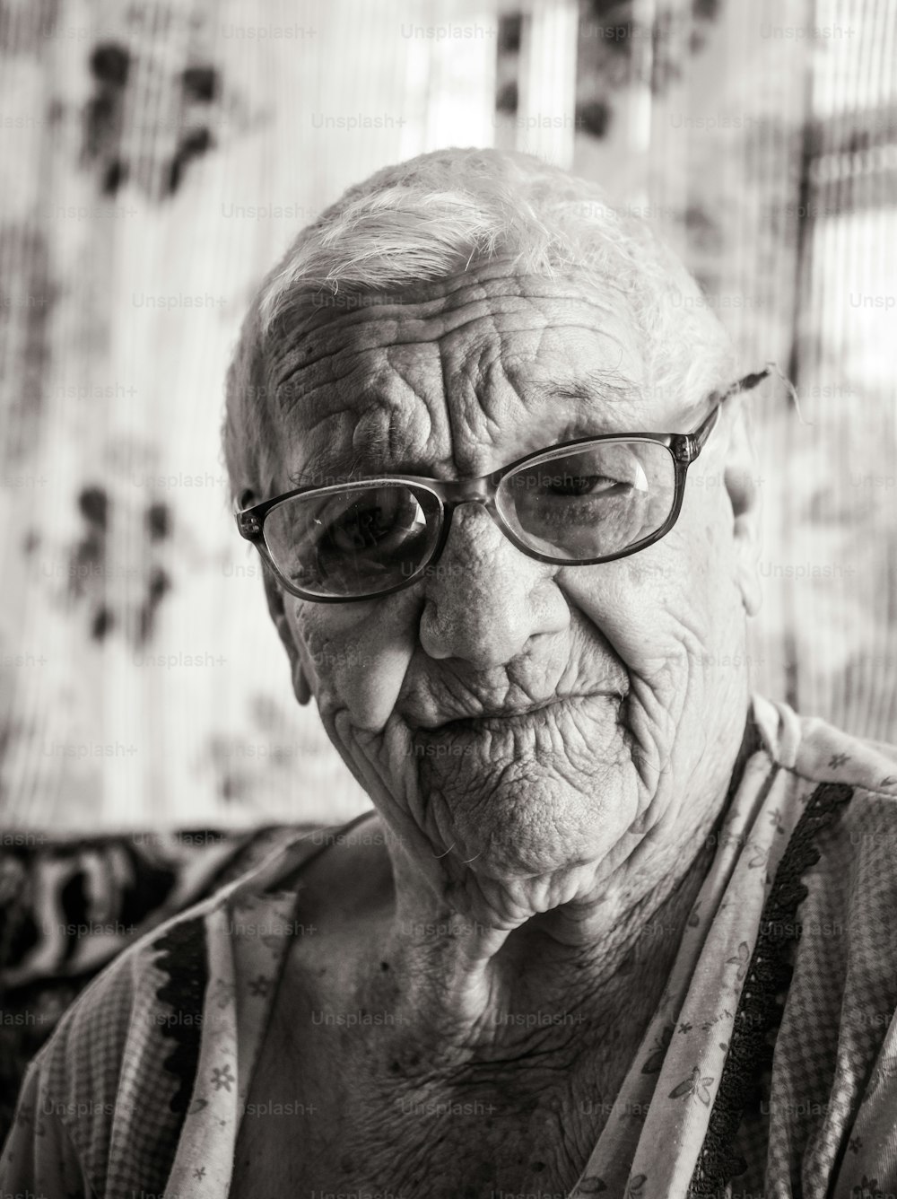 Black and white portrait of an old wrinkled hundred-year-old woman. A smiling grandmother wearing big glasses. Age, kindness and wisdom