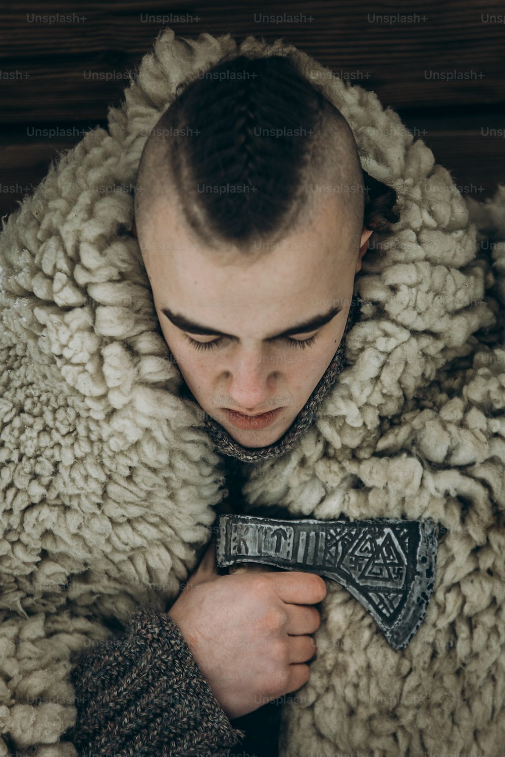 Portrait de Viking, fort beau guerrier viking avec rituel de hache en acier avant la bataille, cosplay de Thor, vêtements de costume historique scandinave, ancien guerrier avec le visage mohawk en gros plan