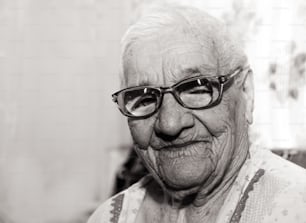 Retrato em preto e branco de uma velha mulher enrugada de cem anos de idade. Uma avó sorridente usando óculos grandes. Idade, bondade e sabedoria