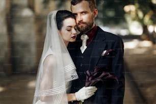 elegant gorgeous bride and stylish handsome groom in sunlight posing. unusual luxury wedding in retro style with bouquet of calla. amazing romantic moment