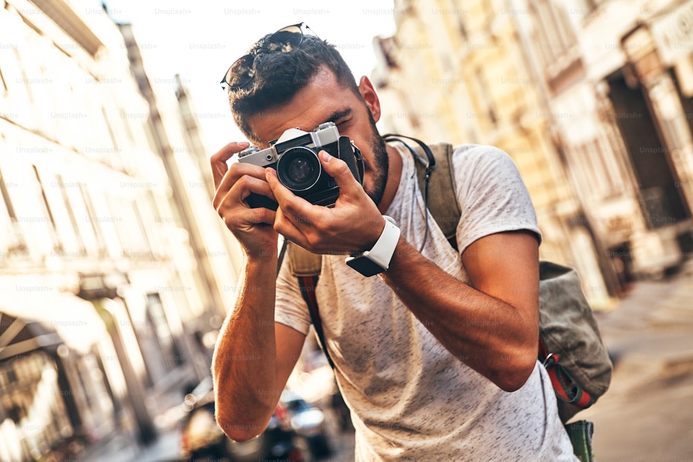 Young man in casual clothing photographing you while standing outdoors