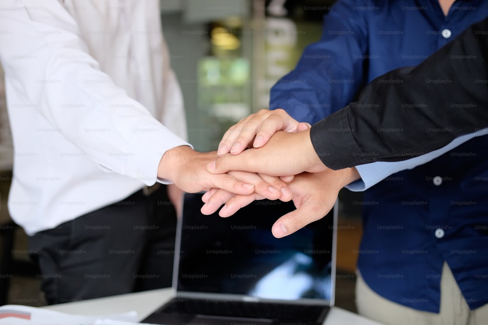 Close up young business people putting their hands together. Stack of hands on office workplace. Unity and teamwork concept.