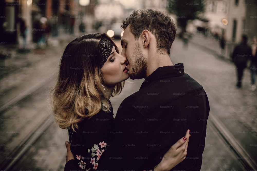 Stilvolles Zigeunerpaar verliebtes Küss Umarmung in der abendlichen City Street. Frau und Mann umarmen sich sanft, romantischer französischer atmosphärischer Moment. Liebesstimmung. Zigeunerhochzeit