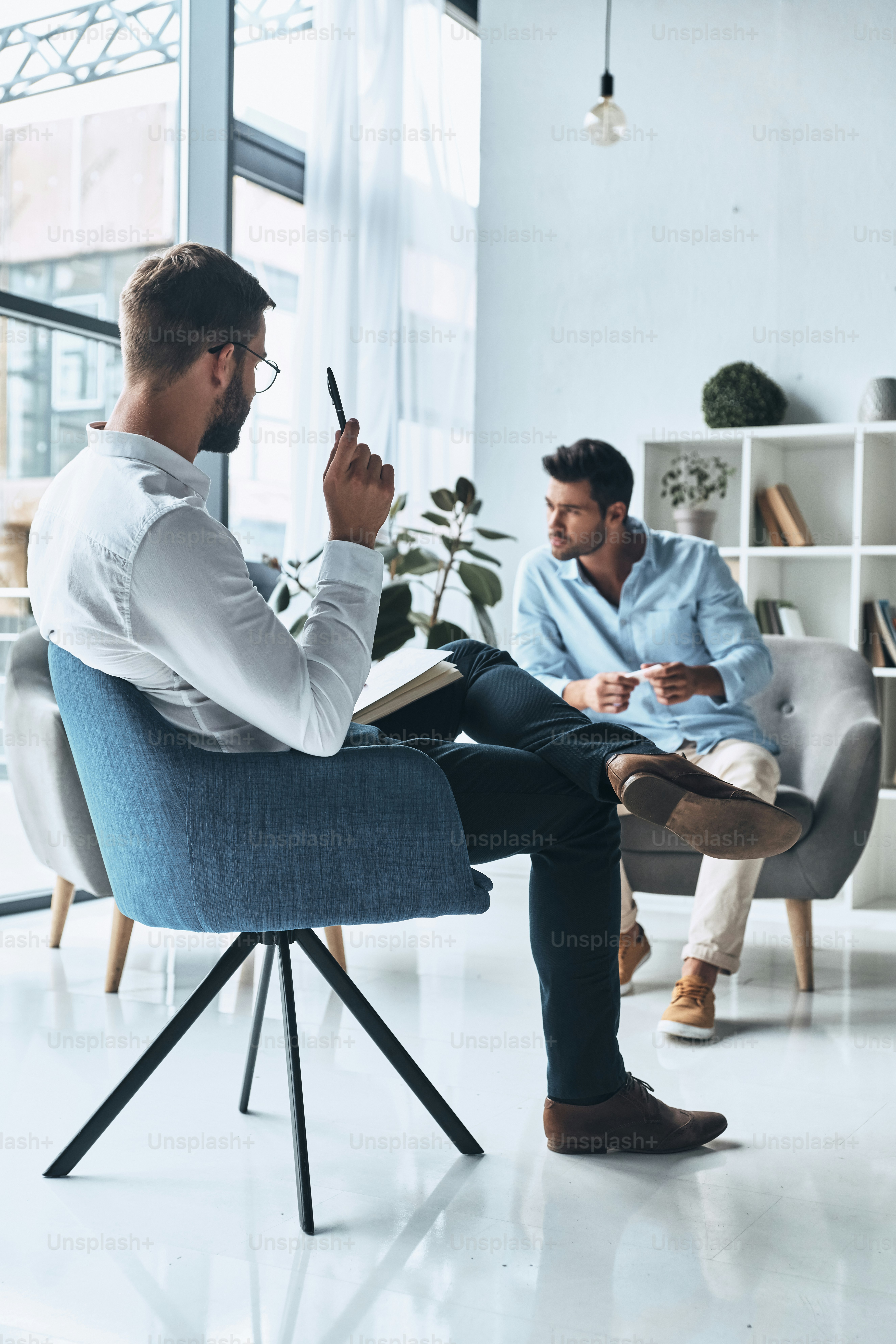 Young frustrated man solving his mental problems while having therapy session with psychologist