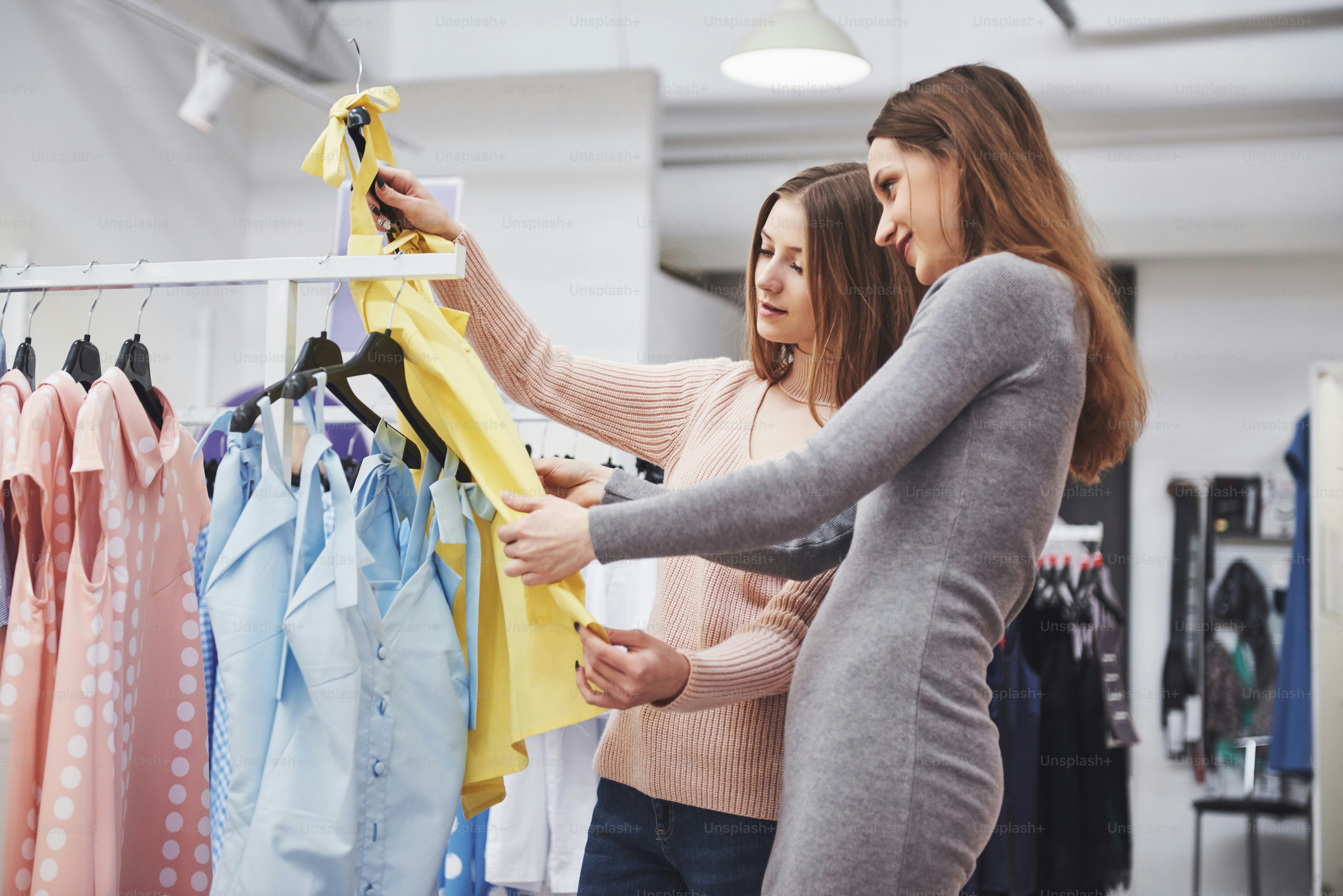 Young beautiful women at the weekly cloth market - Best friends sharing free time having fun and shopping.