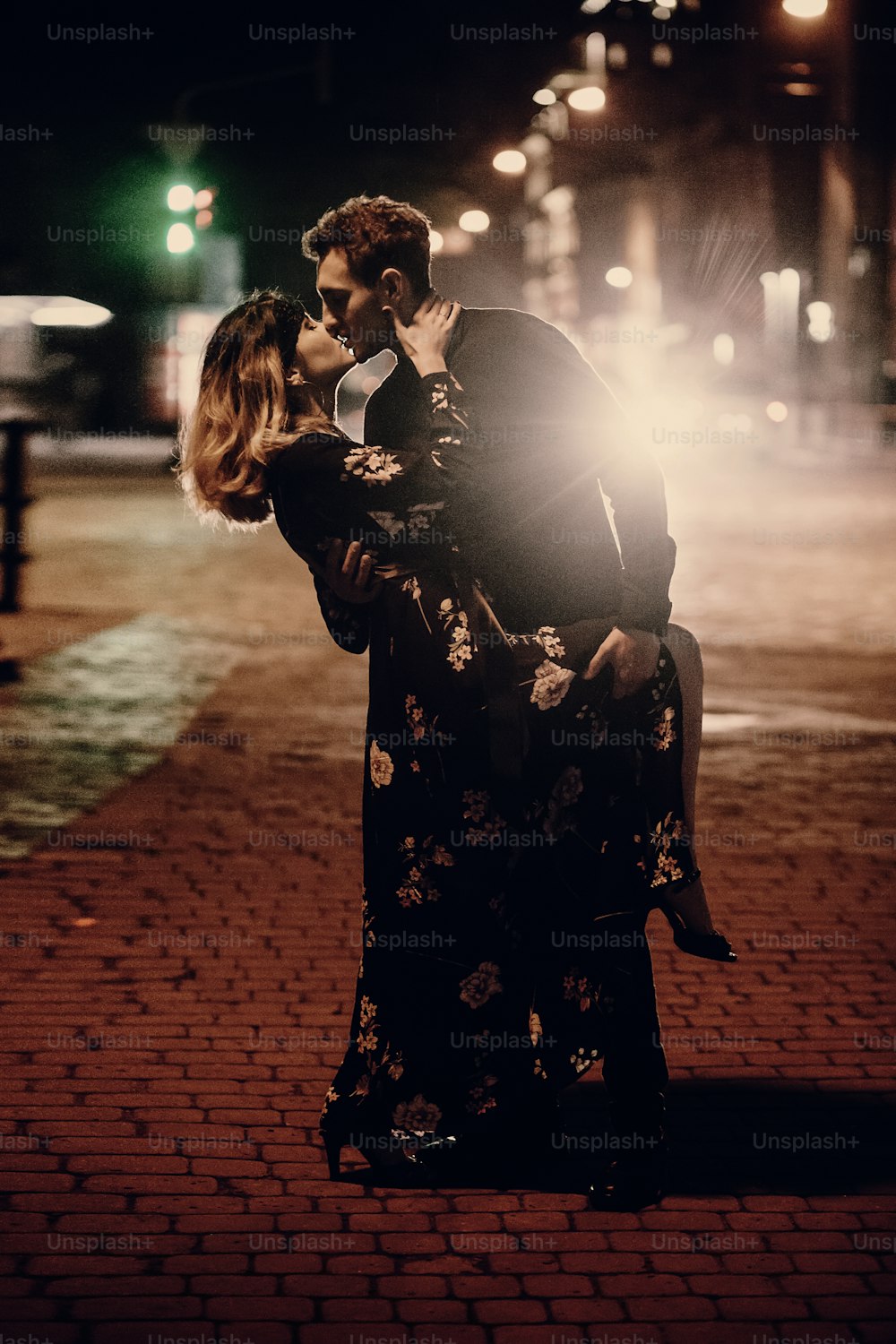 passionate lovers kissing in evening city street under lantern. stylish couple in love embracing in city lights. modern woman and man romantic french atmospheric moment.