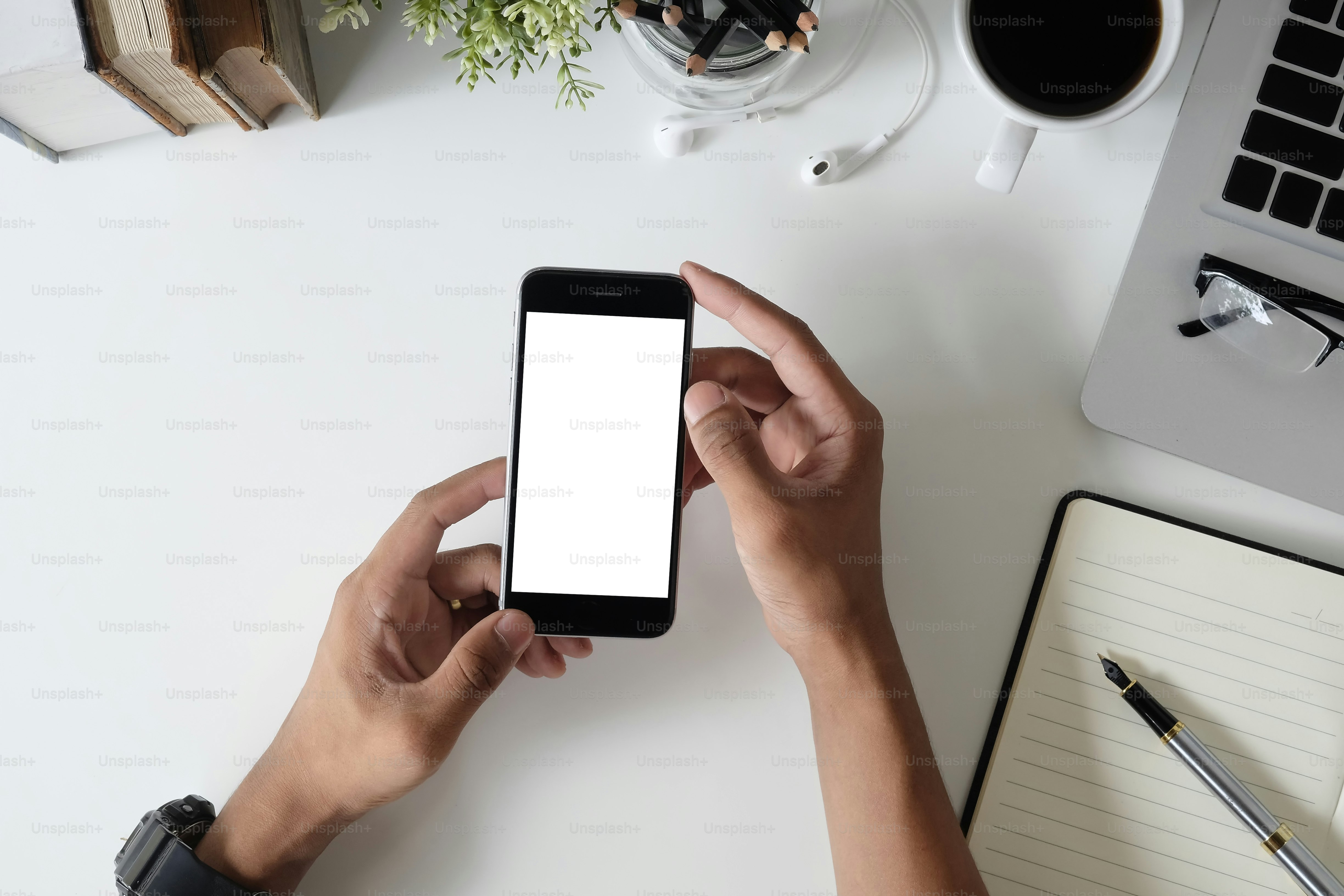 Top-View-Schreibtisch mit Mockup-Smartphone auf Händen mit leerem Bildschirm.