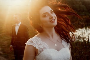 Magnifique mariée et le marié s’amusant et sautant dans la douce lumière du soir au coucher du soleil. Moment émouvant d’un beau couple de mariage à l’extérieur