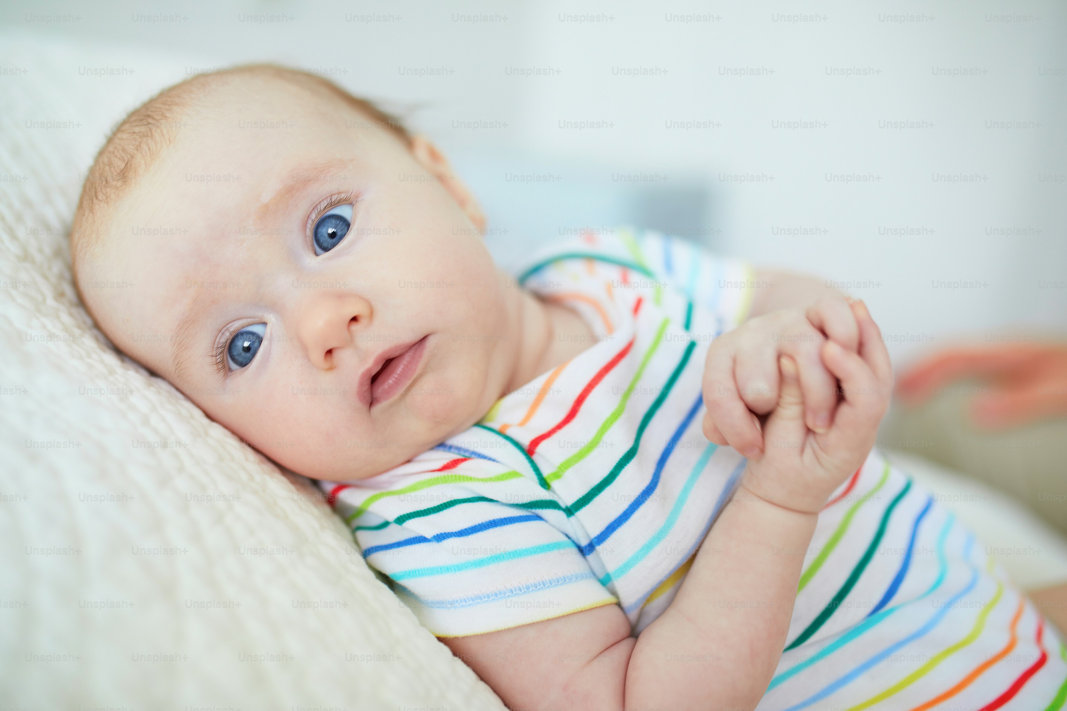 Adorable blue eyed 3 months old baby girl in colorful clothes at home