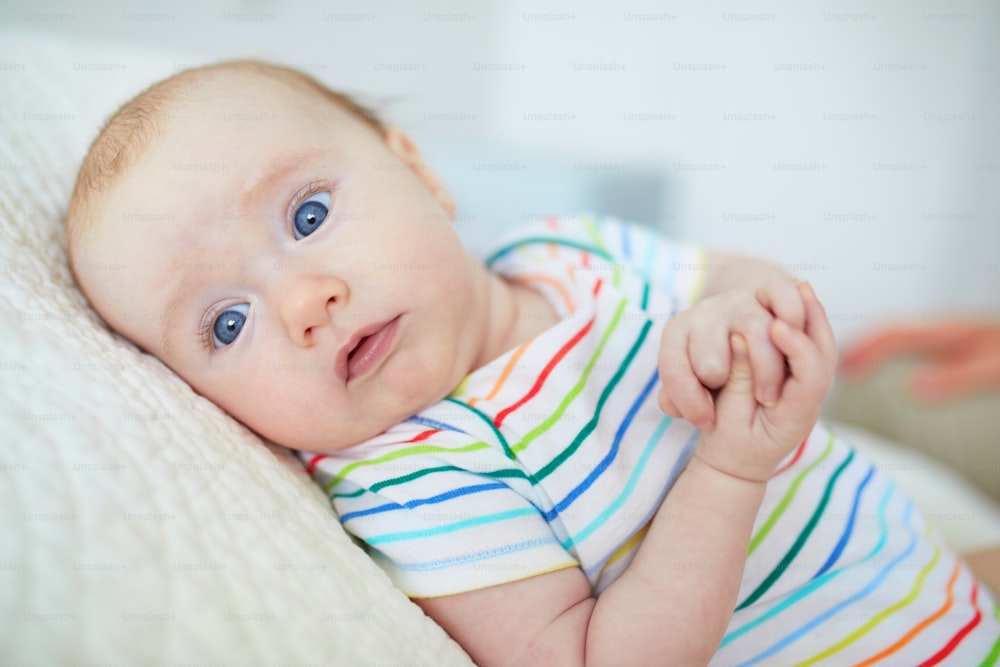 Adorable blue eyed 3 months old baby girl in colorful clothes at home