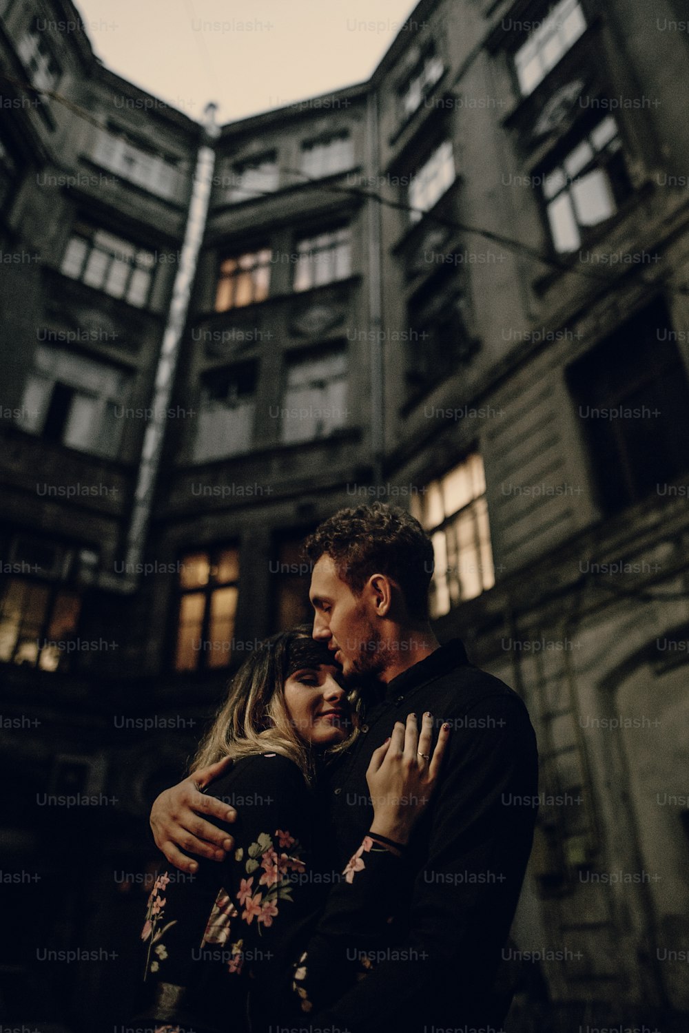 stylish gypsy couple in love embracing in evening city street at old building. woman and man gently hugging, romantic french atmospheric moment. love mood. modern bride and groom