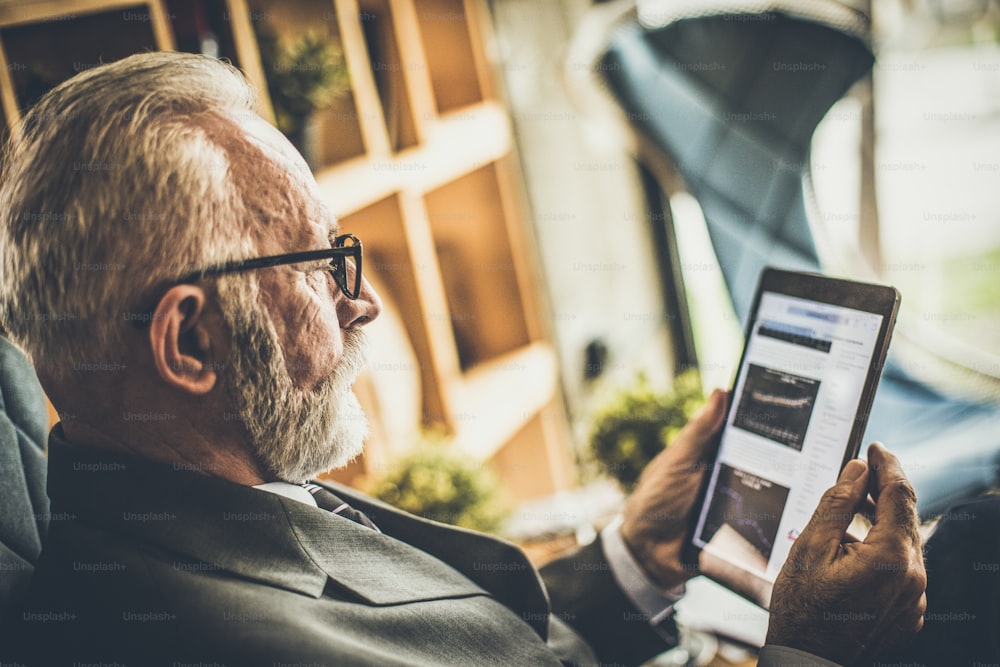 Senior businessman working on his digital tablet. Close up.