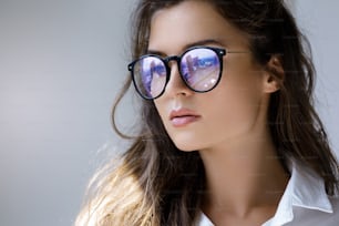Donna d'affari premurosa che pensa al futuro. Ritratto ravvicinato di giovane donna con un riflesso della città moderna all'interno di occhiali.
