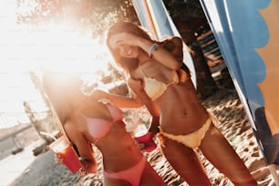 Two attractive young women smiling and enjoying cocktails while having fun on the beach