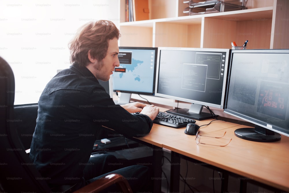 소프트웨어 개발 회사의 사무실에서 많은 모니터가 있는 데스크톱 컴퓨터에서 작업하는 남성 프로그래머. 웹 사이트 디자인 프로그래밍 및 코딩 기술.
