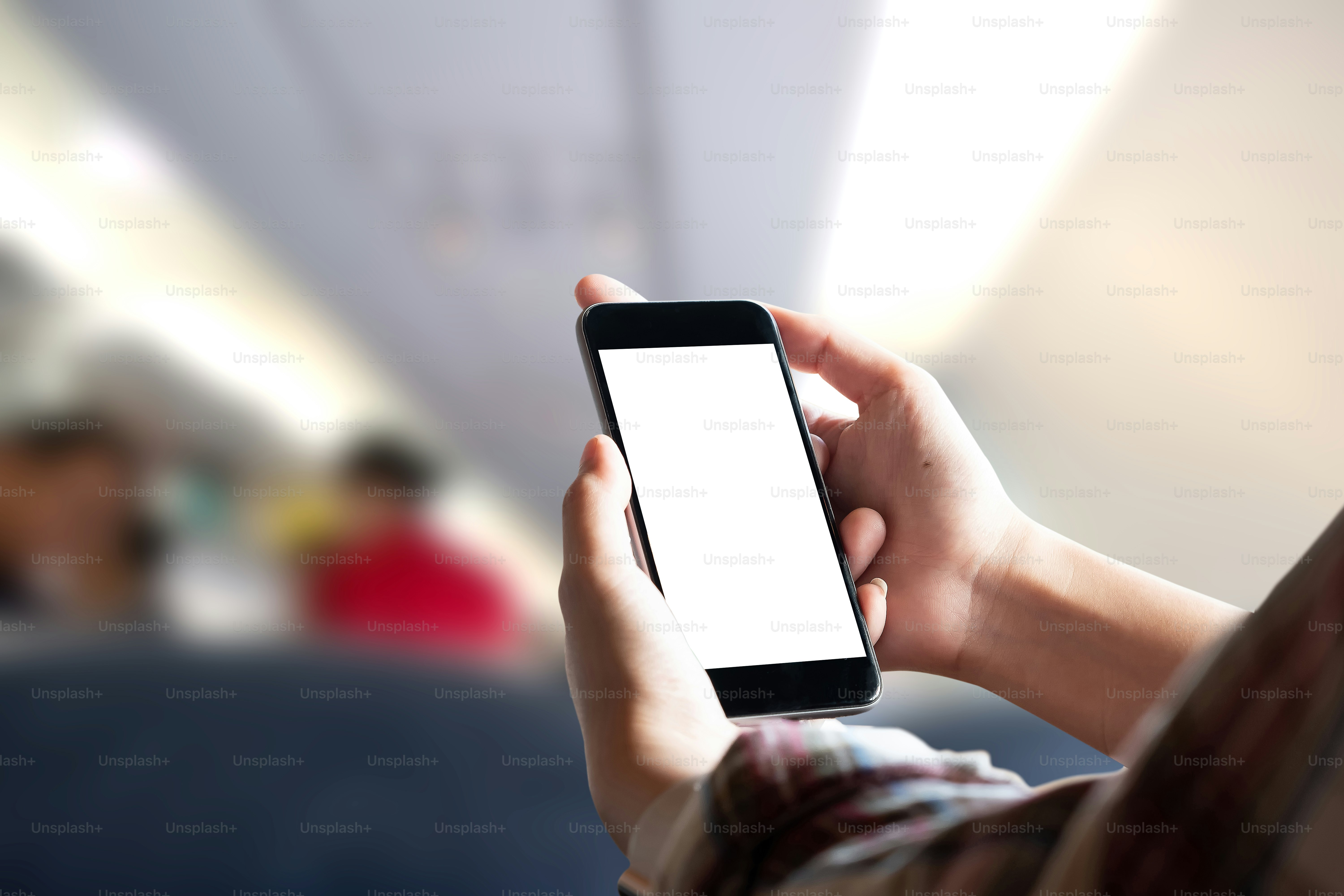 Airplane passenger using smart phone on plane. Businessman touching blank screen mobile phone at airplane. for graphics display montage.