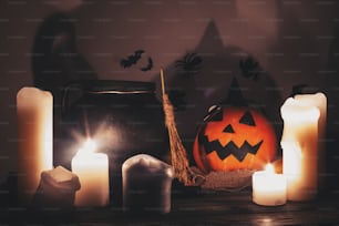 Feliz Halloween. Calabaza de calabaza de calabaza con velas, cuenco, escoba de bruja y murciélagos, fantasmas en el fondo en una habitación oscura y espeluznante. Imagen de Halloween de otoño. Momento atmosférico aterrador