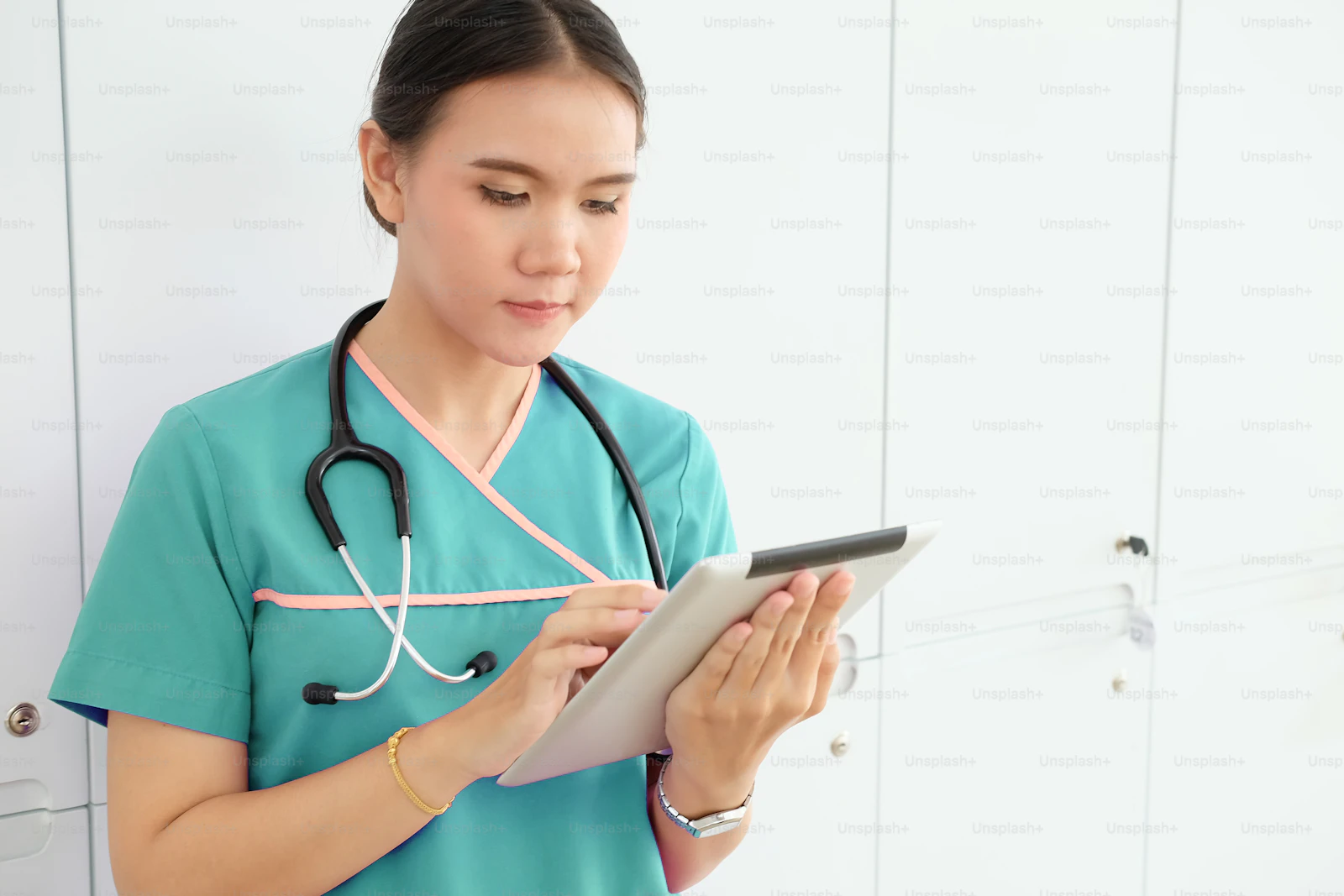 An Asian healthcare professional reviewing patient data on a tablet in a clinical setting