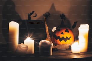 暗い不気味な部屋の背景にろうそく、ボウル、魔女のほうきとコウモリ、幽霊とジャックOランタンカボチャ。ハッピーハロウィンのコンセプト。秋のハロウィーン画像