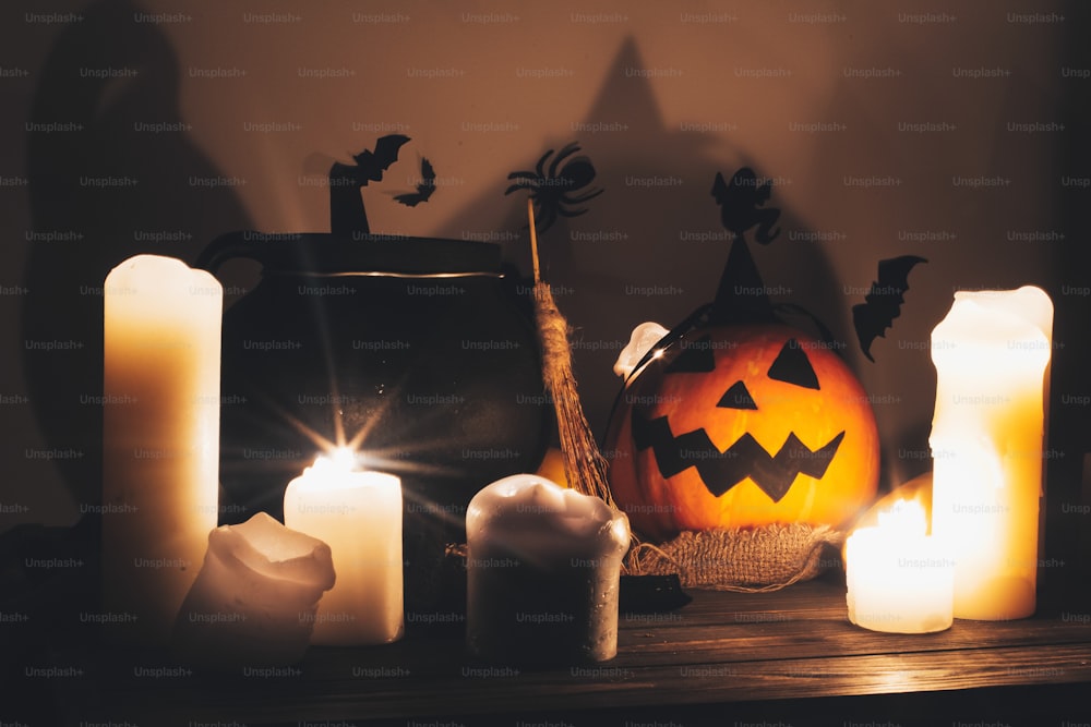 calabaza de jack o linterna con velas, cuenco, escoba de bruja y murciélagos, fantasmas en el fondo en habitación oscura y espeluznante. Concepto de feliz Halloween. Imagen de Halloween de otoño