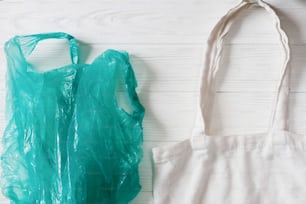 プラスチックを禁止する。ショッピング用のエコナチュラル再利用可能なトートバッグ付きビニール袋、素朴な背景に平らな置き。サステナブルなライフスタイルのコンセプト。廃棄物ゼロ。プラスチックフリーのアイテム。リユース、リデュース、リフューズ、