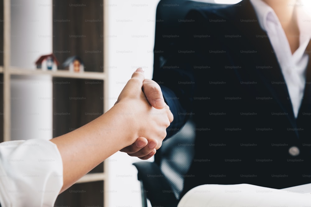 Estate agent shaking hands with his customer after contract signature at modern office