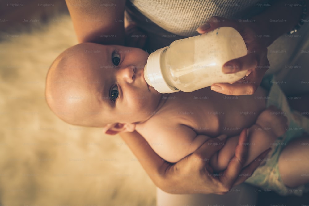 아기에게 우유 한 병을 먹이는 어머니의 초상화.