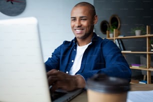 Immagine di un uomo d'affari afroamericano che lavora sul suo laptop. Bel giovane alla sua scrivania.