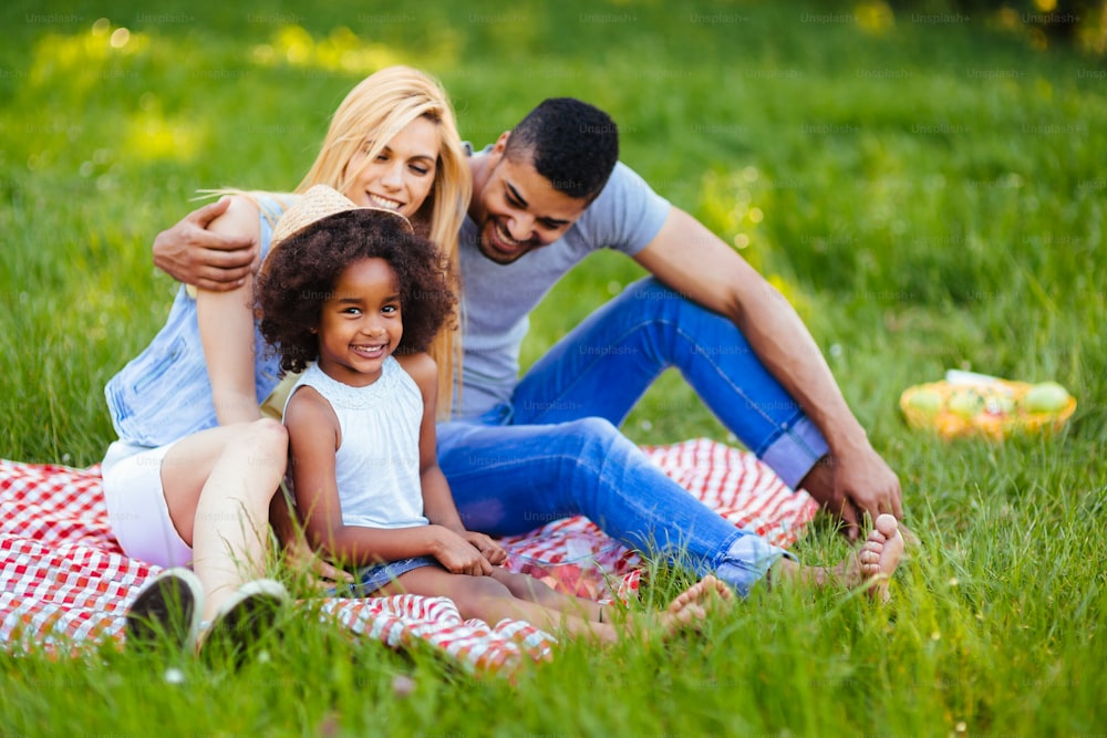 Foto di una bella coppia con la figlia che fa un picnic nella natura