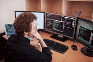 Male programmer working on desktop computer with many monitors at office in software develop company. Website design programming and coding technologies.