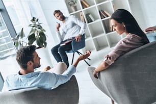 Young married couple talking while sitting on the therapy session with psychologist