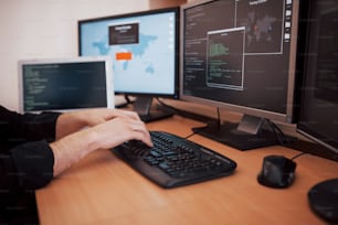 O jovem hacker perigoso quebra os serviços do governo baixando dados confidenciais e ativando vírus. Um homem usa um laptop com muitos monitores.