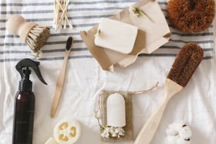 sustainable lifestyle concept, zero waste flat lay. natural eco luffa, bamboo toothbrush, brush, coconut soap, handmade detergent and crystal deodorant on towel, bathroom essentials