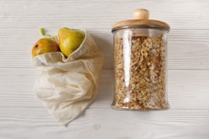 eco natural bags with fruits and granola in glass, flat lay. plastic free items. reuse, reduce, recycle, refuse. bulk store. sustainable lifestyle concept. zero waste.