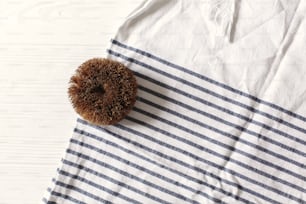 zero waste concept. natural plastic free coconut brush for kitchen and bathroom cleaning on towel on white wood. sustainable lifestyle
