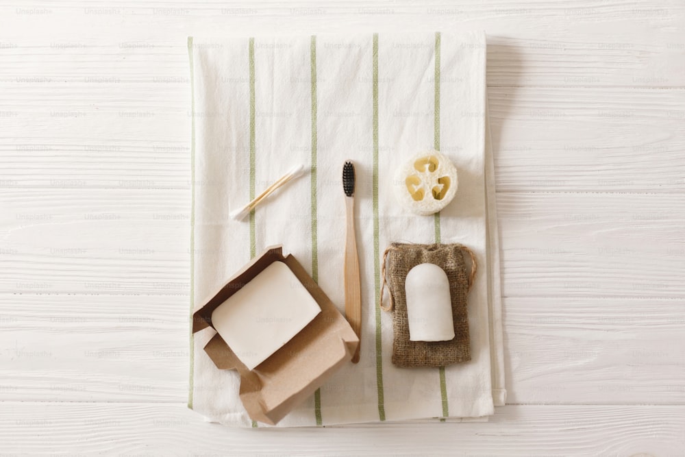 sustainable lifestyle, zero waste concept. natural eco bamboo toothbrush, crystal deodorant,coconut soap,ear sticks,luffa on towel, flat lay.  plastic free items for  hygiene