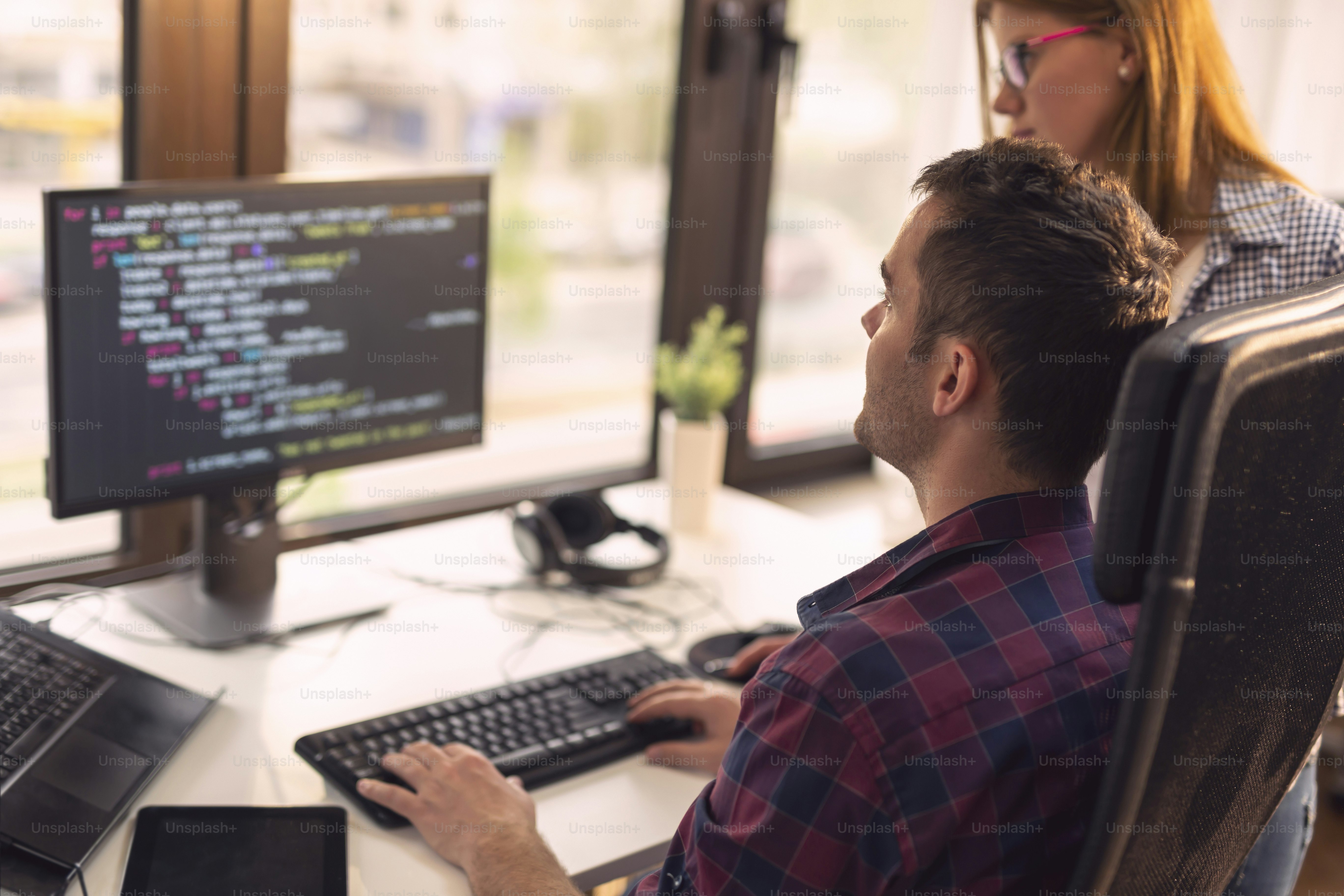 Dua pengembang senior bekerja di kantor perusahaan pengembang perangkat lunak. Fokus pada pria duduk