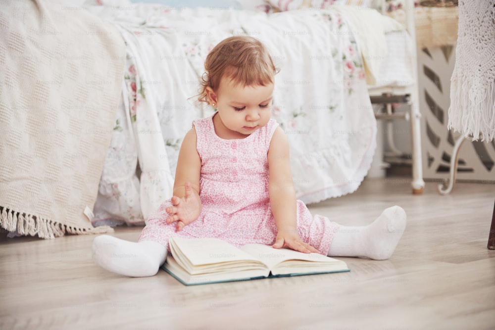 Beautiful little girl playing toys. Blue-eyed blonde. White chair. Children's room. Happy small girl portrait. Childhood concept.