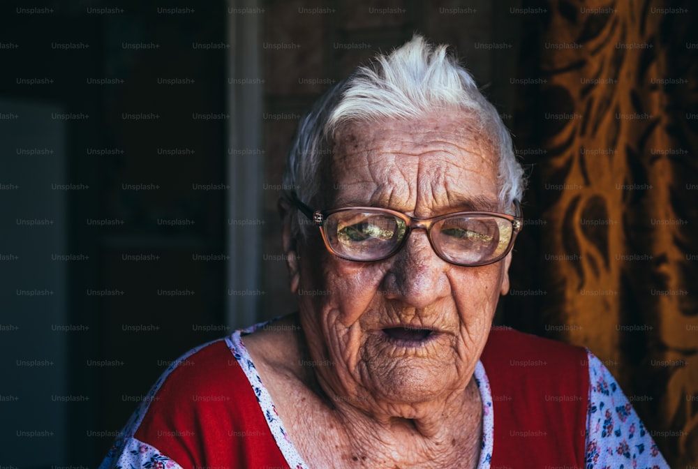 Ritratto di una vecchia donna centenaria rugosa. Una nonna sorridente che indossa grandi occhiali. Età, gentilezza e saggezza