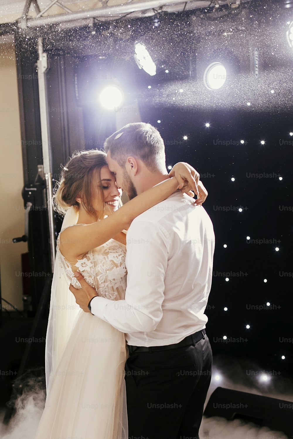 Gorgeous bride and stylish groom gently dancing at wedding reception. Happy wedding couple performing first dance in restaurant. Romantic moments of newlyweds