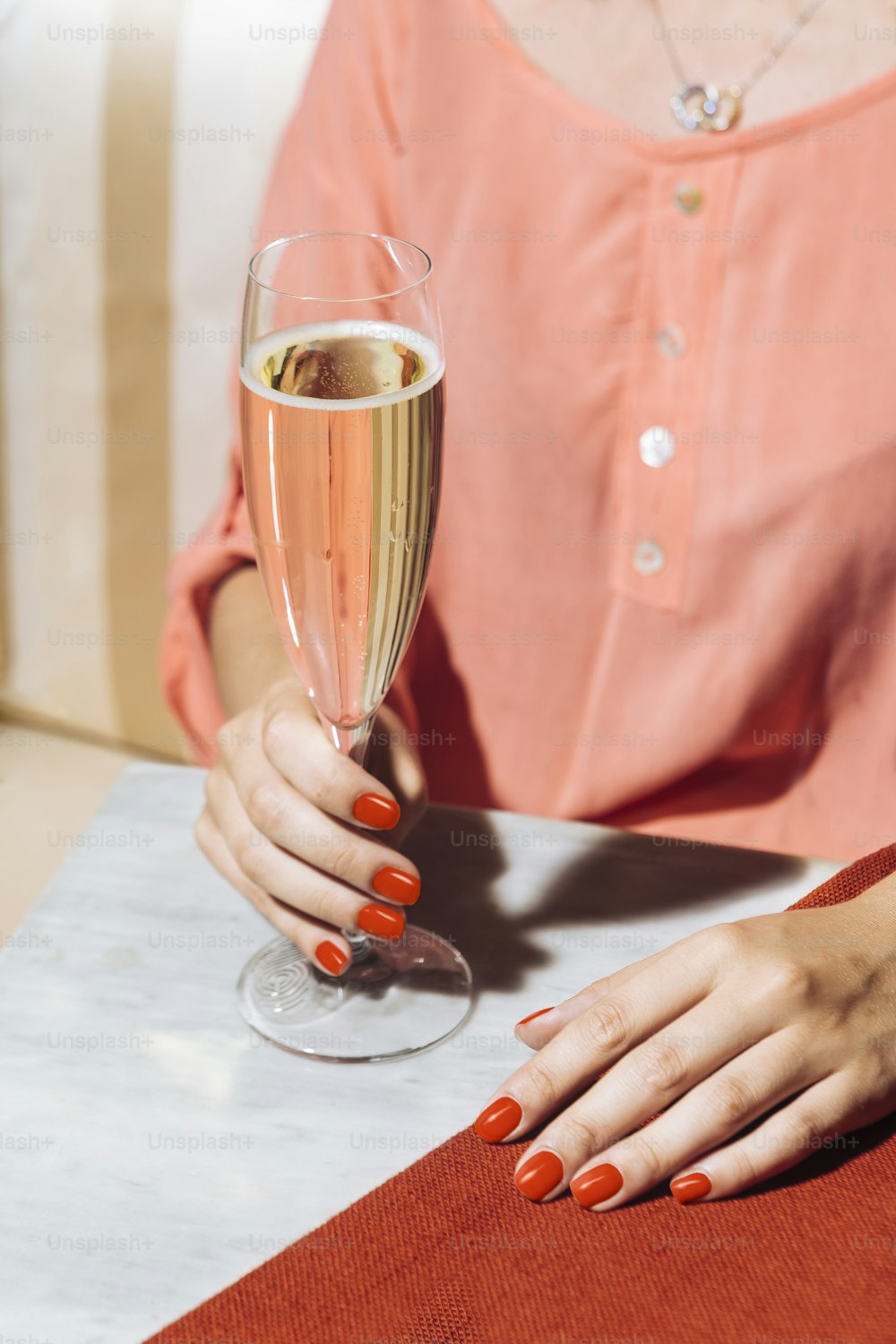 A glass of prosecco held by a girl in an elegant bar with vintage pop colors