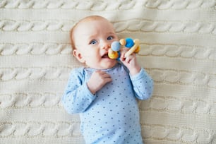 Newborn baby girl playing with colorful teething toy. Development games for infants