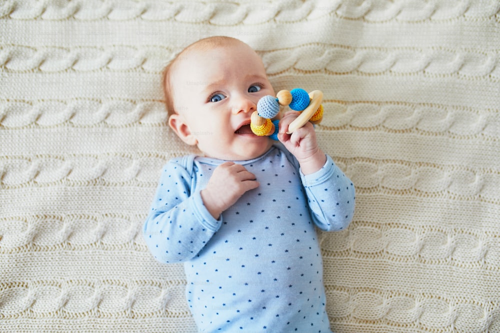Niña recién nacida jugando con un colorido juguete para la dentición. Juegos de desarrollo para bebés