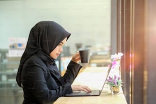 Attractive female Arabic working on laptop computer on desk.