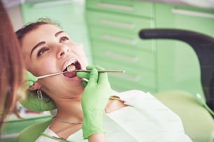 Odontólogo curando a una paciente femenina en estomatología. Concepto de prevención temprana e higiene bucal.