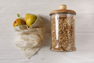 granola in glass and eco natural bags with fruits, flat lay. plastic free items. reuse, reduce, recycle, refuse. bulk store. sustainable lifestyle concept. zero waste.