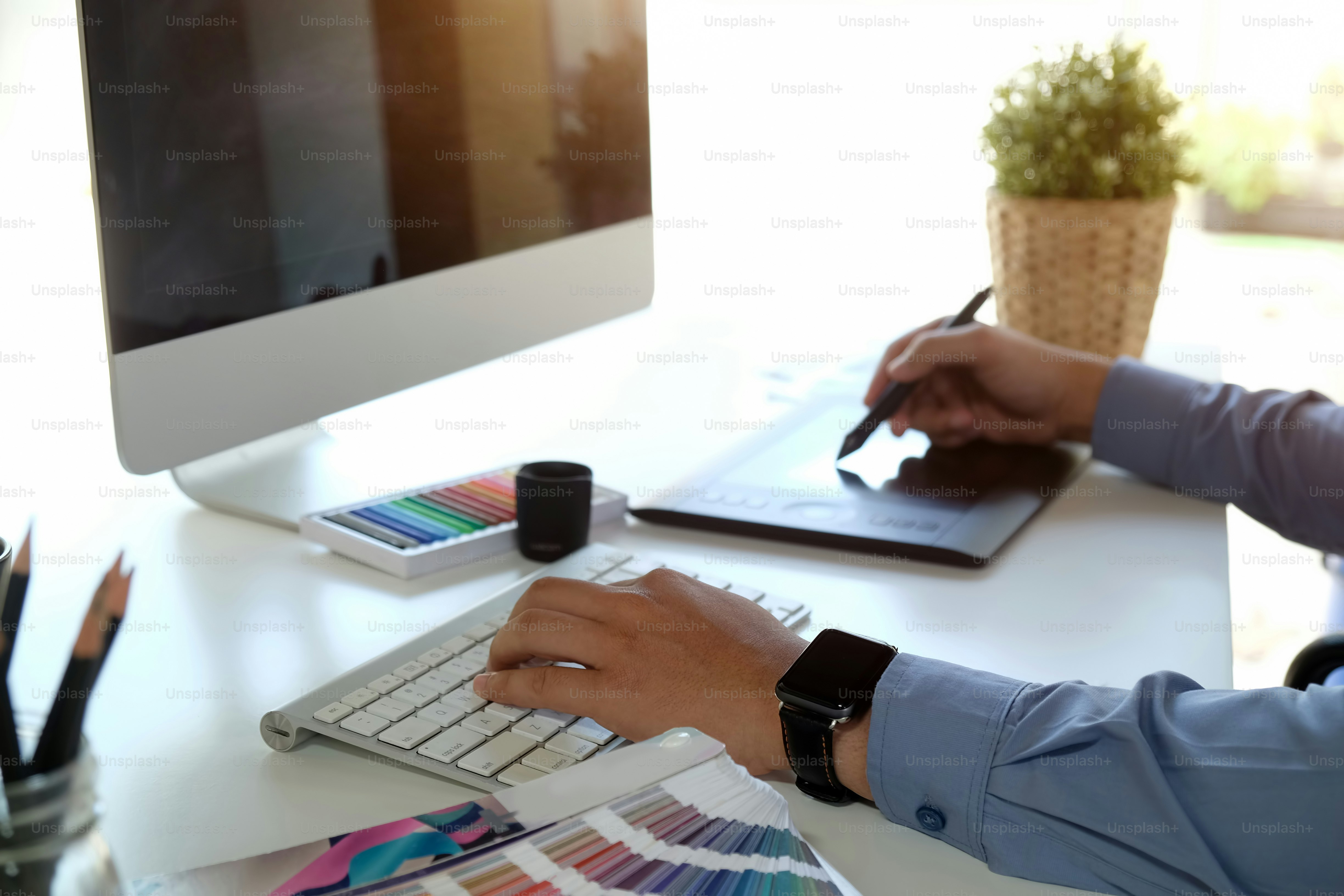 Graphiste travaillant sur un ordinateur de bureau moderne tout en utilisant une tablette graphique au bureau au bureau