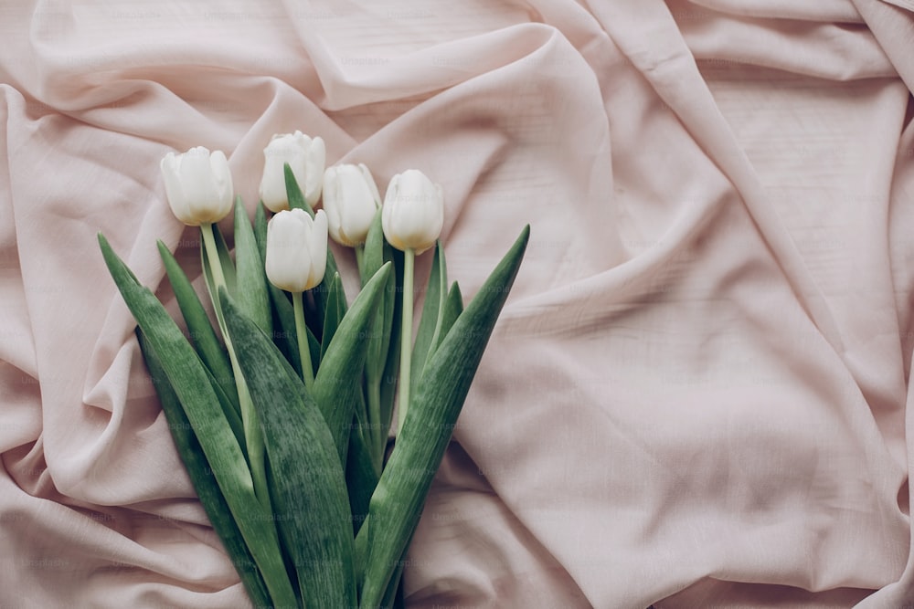 Instagram Spring Flat Lay. Elegantes tulipanes blancos sobre tela suave beige sobre fondo de mesa rústica vista superior. luz suave, momento atmosférico de ternura. espacio para el texto. Boda rústica