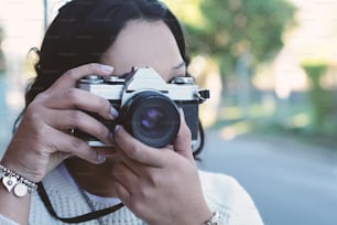 portrait of young woman having fun taking photos with retro film camera. Outdoor lifestyle portrait.